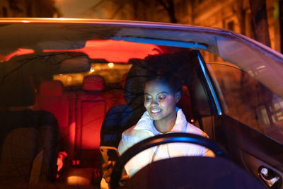 Black woman driver hold smartphone sitting on driver seat in car. woman use gps navigation to drive