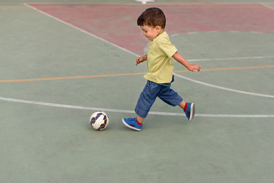 Full length of cute boy playing soccer