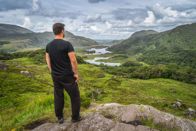 Rear view of man standing on mountain against sky