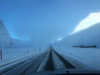 Cropped image of car on road amidst snowcapped mountains
