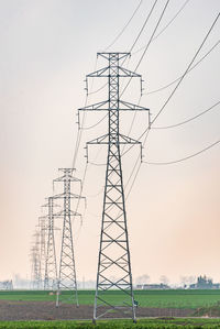 Low angle view of electricity pylon on field against sky