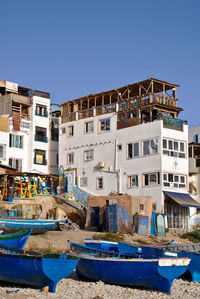 Buildings by canal against clear blue sky
