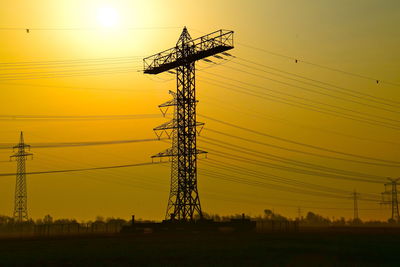 Silhouette electricity pylon against sky during sunset