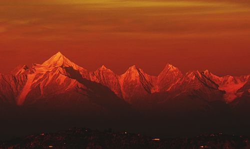 Scenic view of majestic mountains against orange sky