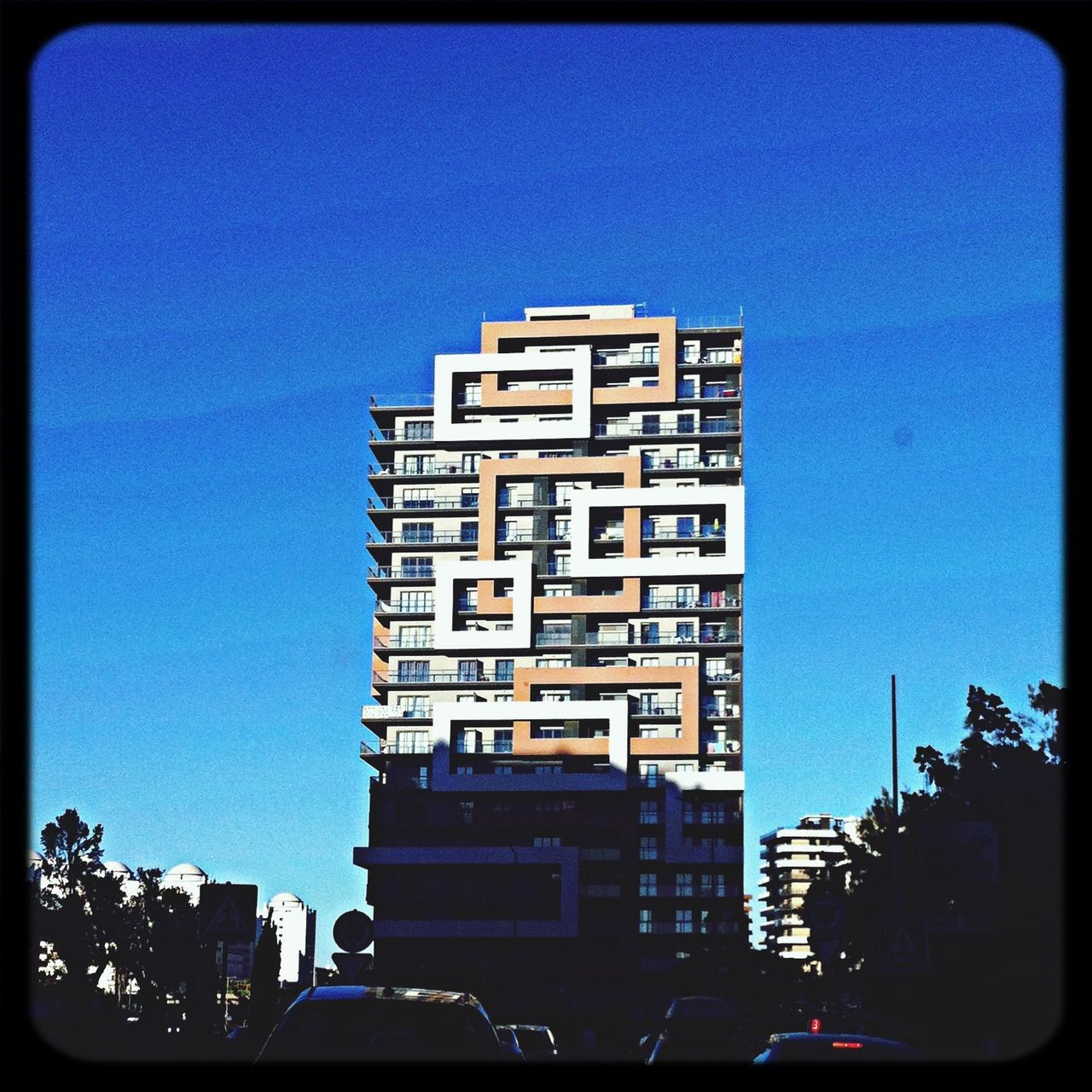 building exterior, architecture, built structure, transfer print, car, clear sky, city, auto post production filter, land vehicle, transportation, low angle view, blue, building, street, mode of transport, residential building, copy space, city life, city street, sky