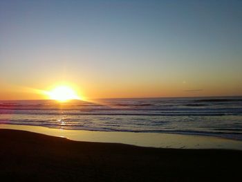 Scenic view of beach against clear sky during sunset