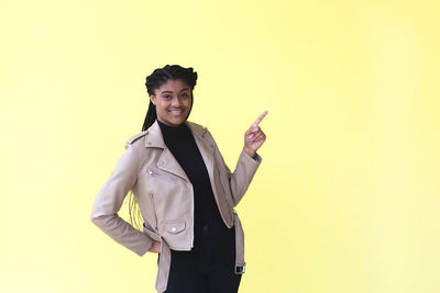 Portrait of smiling young woman against gray background