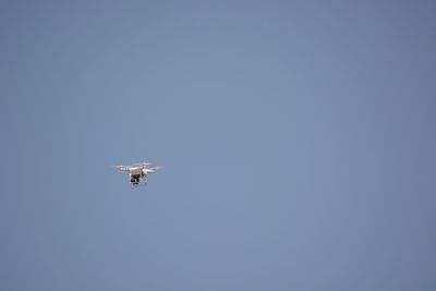 Low angle view of airplane flying against clear blue sky