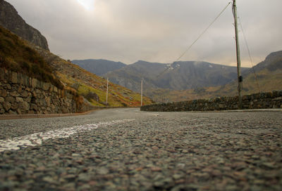 Surface level of road by mountains against sky
