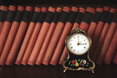 Close-up of clock by books on table