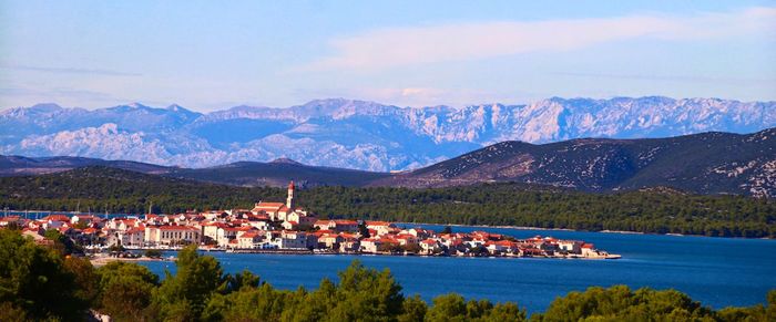 Scenic view of townscape by mountains against sky