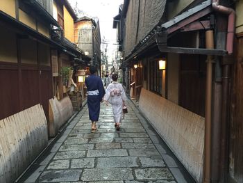 Full length rear view of people walking in alley