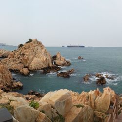 Rocks by sea against clear sky