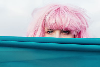 Woman covering face with textile against wall