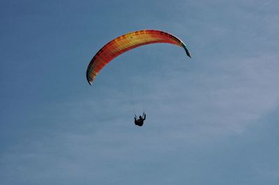 Low angle view of person paragliding against sky