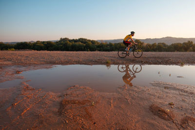 Man riding bicycle on land against sky
