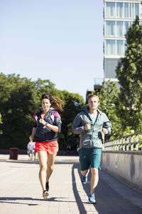 Full length of multi-ethnic couple jogging on bridge