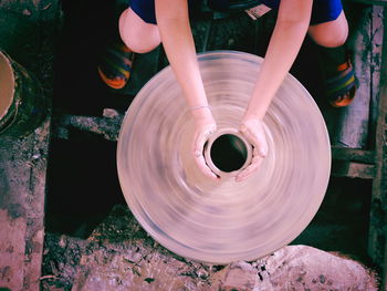 Low section of woman shaping earthenware on pottery wheel