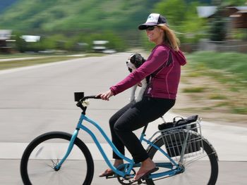 Puppy with young woman riding bicycle on road