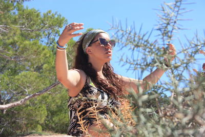 Low angle view of woman looking away against trees