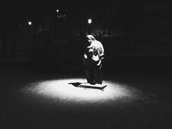 Full length of man standing against illuminated lamp