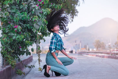 Teenage girl with tousled hair on roadside by plants