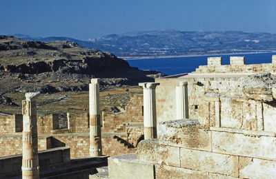 Built structure by sea against mountains