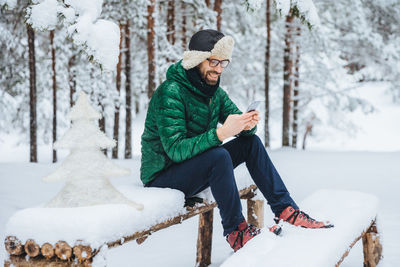 Man using mobile phone while sitting on snow