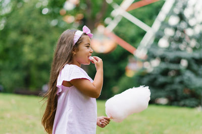 Funny girl in pink dress eats cotton candy in summer in the park person