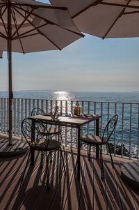 Chairs and table by sea against sky