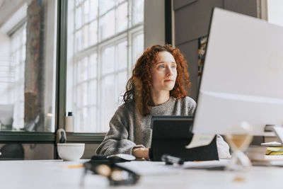 Focused redhead businesswoman working on desktop pc at office