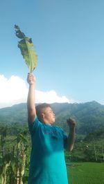 Young man standing on mountain against sky