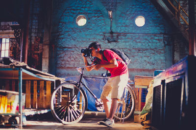 Side view of man standing by bicycle in city