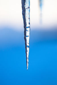 Close-up of frozen water against blue sky