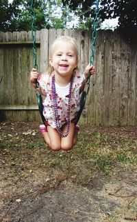 Portrait of smiling girl enjoying swing in yard