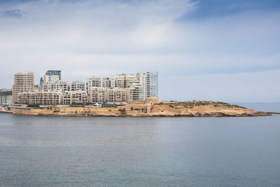 Buildings by sea against sky in city