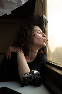 Portrait of young woman looking through window