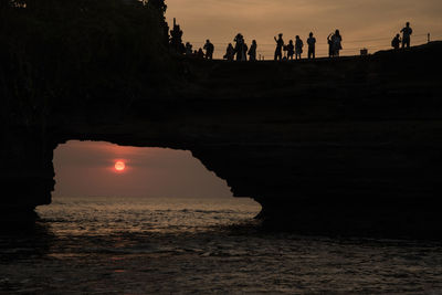 Silhouette people on beach against sky during sunset