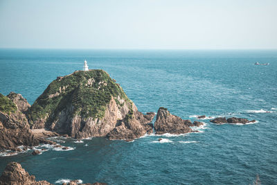 Lighthouse by sea against clear sky