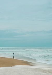 Rear view of woman walking at beach against sky