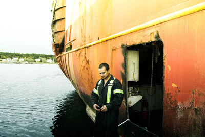 Mechanic standing by boat on lake