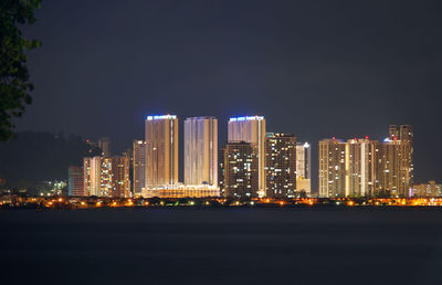 Illuminated buildings in city against sky at night