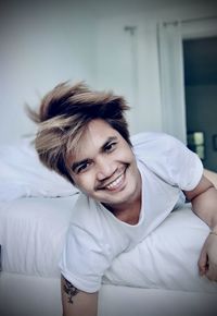 Portrait of smiling young men relaxing on bed at home