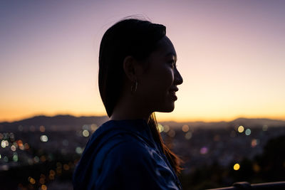 Happy ethnic tourist against city and sunset sky