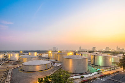 Illuminated factory against sky during sunset