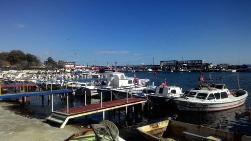 Boats moored at harbor against clear blue sky