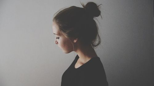 Close-up side view of a young woman over grey background