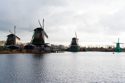 Traditional windmill by water against sky