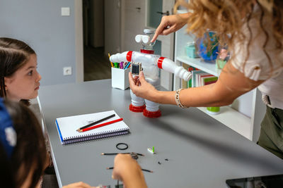 Teacher in a robotics class showing solar panel over recycled toy robot