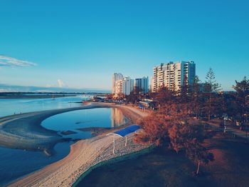 Scenic view of beach and buildings against clear blue sky